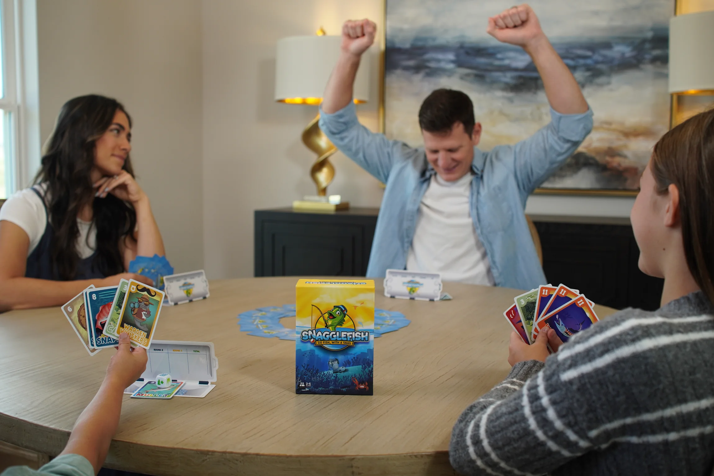 Family playing Snagglefish together around a table, with game box and cards